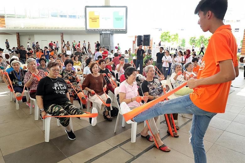 A Temasek Polytechnic student teaching elderly residents stretching exercises with bands during the inaugural Silver Fitness and Wellness Carnival at Bedok Town Square yesterday.