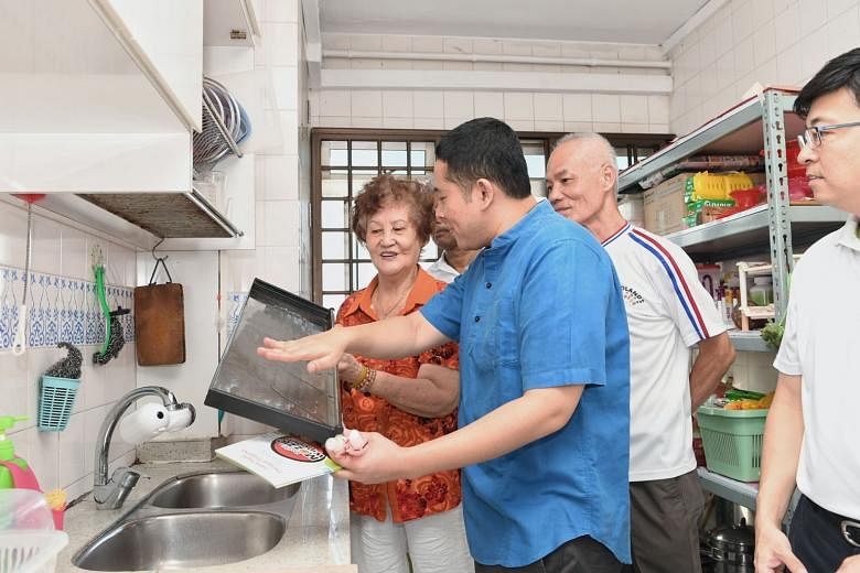 Senior Parliamentary Secretary for Home Affairs and Health Amrin Amin (in blue shirt) sharing tips on removing mosquito-breeding sources with Madam Kung Ah Lor during a home visit yesterday in Woodlands as part of the NEA's dengue prevention outreach