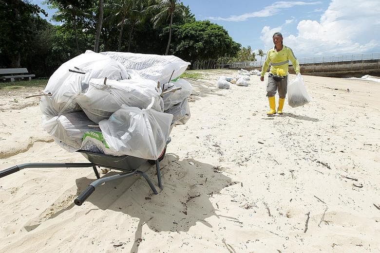 Above: A worker cleaning up the beach. According to the National Environment Agency website, offshore detritus drifts onto the shores of Singapore during the south-west monsoon months from May to October, and the beaches are cleaned more often during