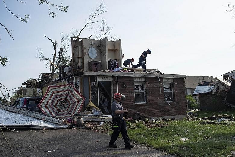 Firefighters and rescue crews searching houses for people trapped or injured following powerful storms yesterday in the US state of Ohio. PHOTO: AGENCE FRANCE-PRESSE