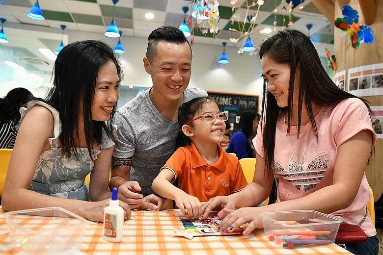 Parents Genevieve and Jeffrey Pang help daughter Sheena make a family photo frame for their helper Yusyie Quimada (right).