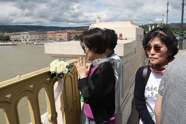 South Koreans mourning yesterday at a bridge over the Danube near the site of the accident involving a cruise ship and a tourist boat. Seven South Koreans were rescued, seven died, and 19 of their compatriots were among the 21 people still missing. P