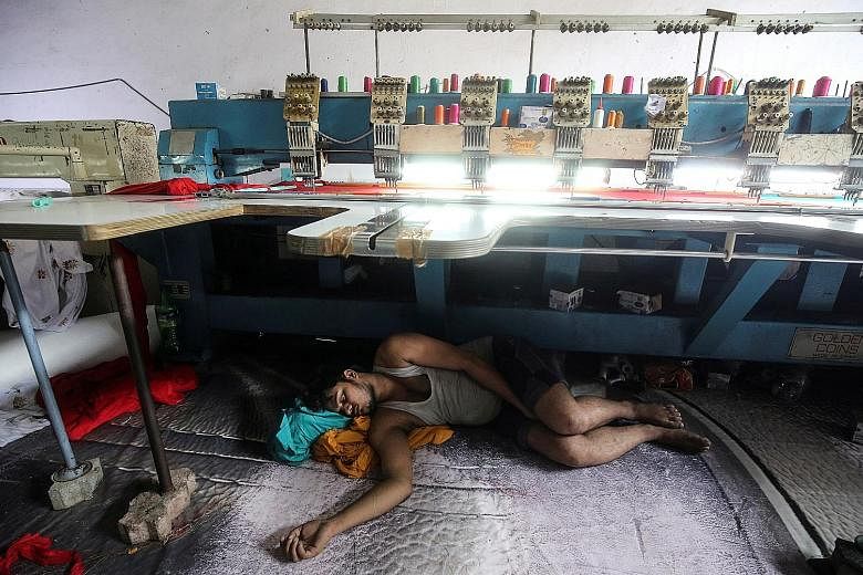A worker sleeping under an embroidery machine in a workshop in Mumbai. The United States' decision to end preferential trade treatment for India comes as official figures show India's growth slowing for the third straight quarter to 5.8 per cent in J