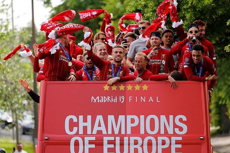 Reds captain Jordan Henderson (front, centre), Trent Alexander-Arnold (front, right) and teammates greet thousands of fans during the bus-top victory parade around Liverpool yesterday.