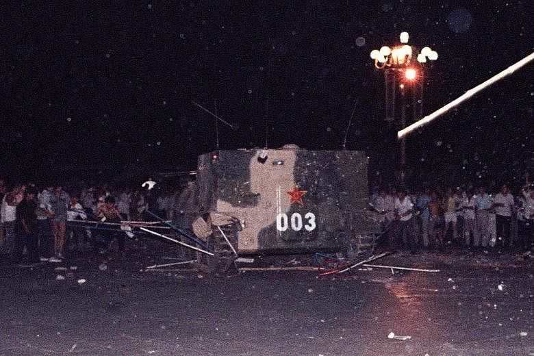Left: A demonstrator flashing the victory sign as workmen used a drape to cover a huge portrait of chairman Mao Zedong at Tiananmen Square in 1989. Above: An armoured personnel carrier crushing one of the tents set up at Tiananmen Square by pro-democ