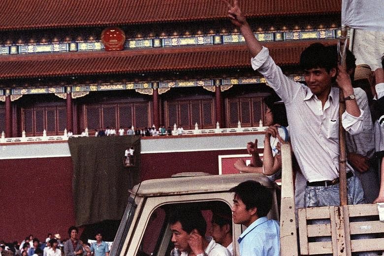 Left: A demonstrator flashing the victory sign as workmen used a drape to cover a huge portrait of chairman Mao Zedong at Tiananmen Square in 1989. Above: An armoured personnel carrier crushing one of the tents set up at Tiananmen Square by pro-democ