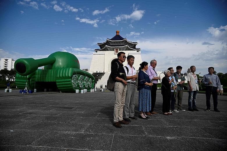 Witnesses of the Tiananmen Square crackdown standing before an inflatable tank sculpture at Chiang Kai-shek Memorial Hall in Taipei yesterday. Activists lighting candles at the Chinese Consulate in the Philippine capital Manila yesterday during a com