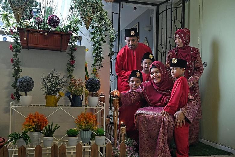 Ms Norkhatilah Maricar with her husband Safza, 43, their children Sohayl, four, Suhaym, six, and Sayf, nine, and maid Leni (standing), 37. They have set up lampu pelita, traditional lamps used during the festivities, outside their flat in Eunos. ST P