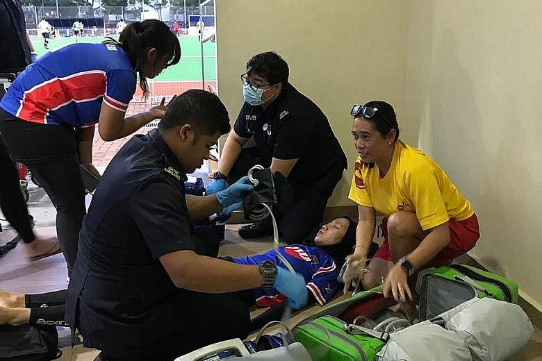 SCDF paramedics treating hockey player Siti Nur Raihanah Waled on Sunday, after she collided with an opponent and suffered a stroke during a National Hockey League match.