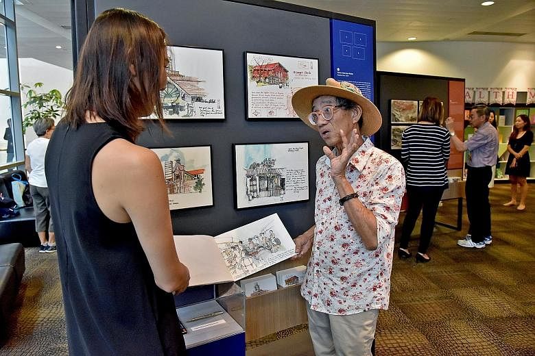 Mr Tony Chua speaking to a visitor about his sketches at Jurong Regional Library yesterday. He is one of three senior Singaporean artists whose pen and watercolour sketches are featured in a new exhibition called Uncles Love Monuments. ST PHOTO: JASM