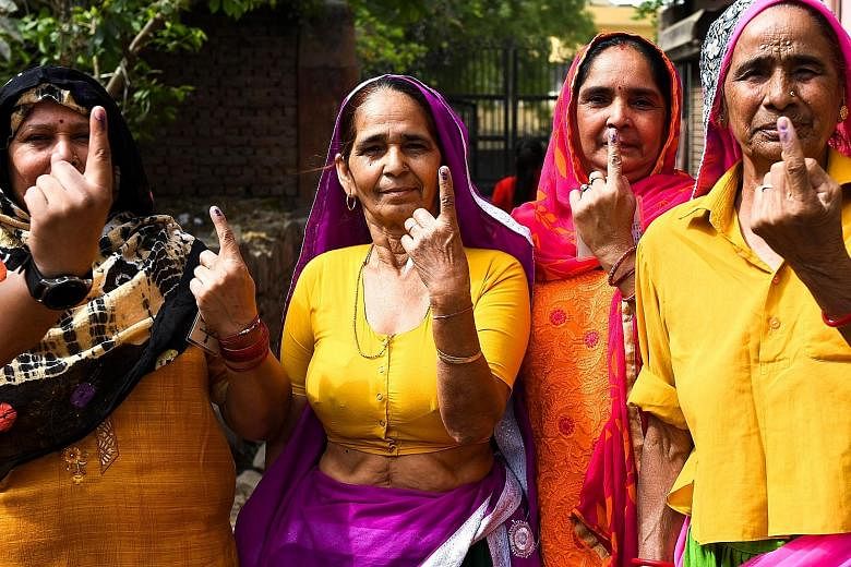 Women showing their ink-marked fingers after voting in last month's general election. Changing demographics has led to a vote in one part of India holding greater value than a vote in another part.