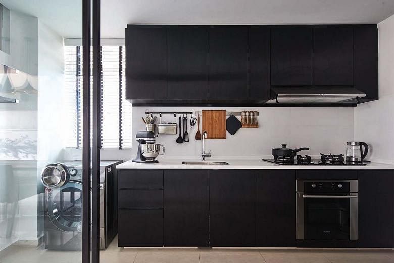 At first glance, the black laminate cladding the kitchen cabinetry appears to be matte. However, it has a striped, stainless steel-like finish, with its sheen offering visual interest in an otherwise simple kitchen.