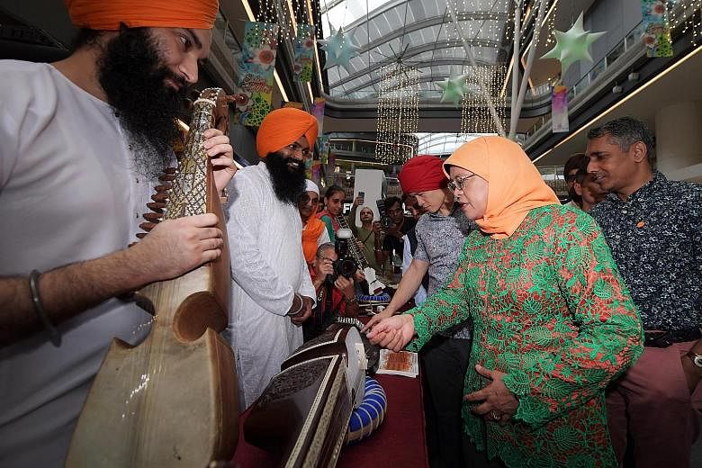 President Halimah Yacob at a booth featuring traditional music instruments during the launch of Sikh Heritage Day at Our Tampines Hub yesterday.