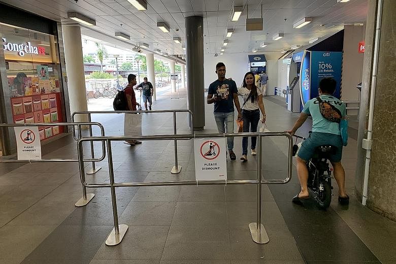 A man riding his personal mobility device through a gap in the metal barriers, which were set up to get riders to dismount inside the Woodlands MRT station compound. SMRT is trialling the use of such barriers to improve safety for commuters. ST PHOTO