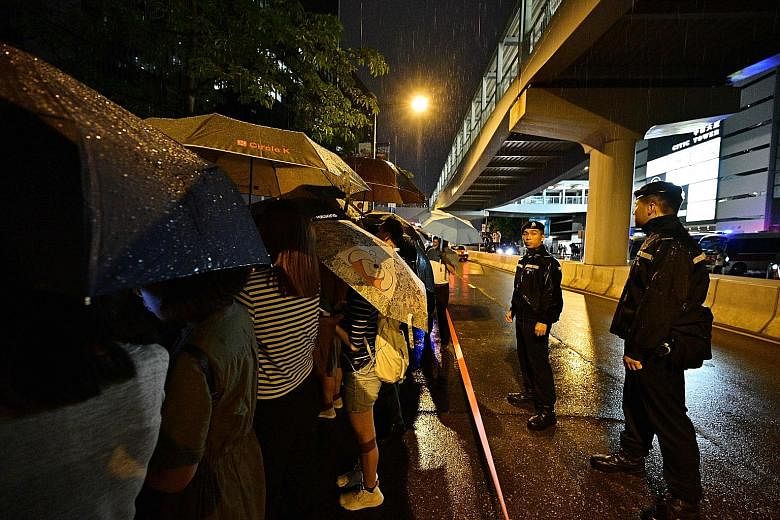 Above: Police standing guard as protesters sang hymns outside the government headquarters yesterday. Left: A group of assistants to members of the Legislative Council speaking to the media outside the LegCo building. Police officers checking the pers