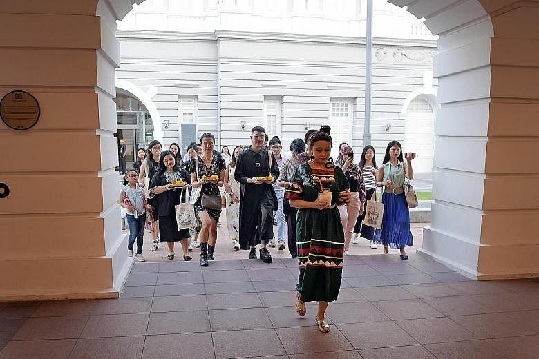 Home-grown artist Zarina Muhammad (foreground) leading members of the press in a ceremonial welcome ritual at the preview of StoryFest on Monday.