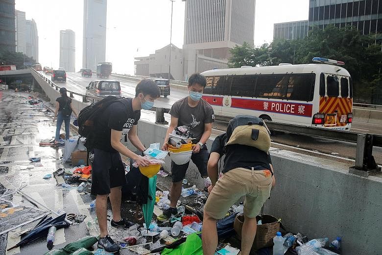 People picking out helmets, umbrellas and other items left behind by protesters in Hong Kong yesterday. Chinese state media blamed Hong Kong's opposition camp and foreign elements for inciting lawlessness. PHOTO: REUTERS