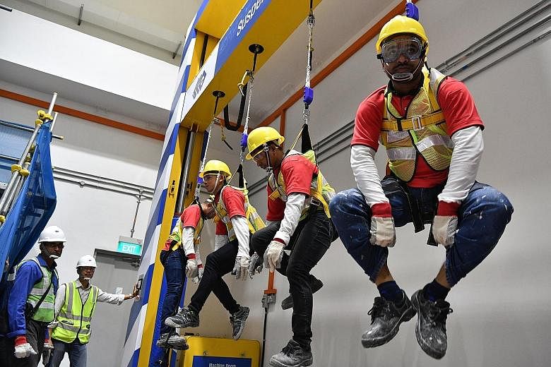 Workers trying out the suspension trauma simulator at the new construction safety school in JTC Space @ Gul. From next month, workers, including supervisors, on all new projects by developer JTC will attend courses at the $2.2 million school. ST PHOT