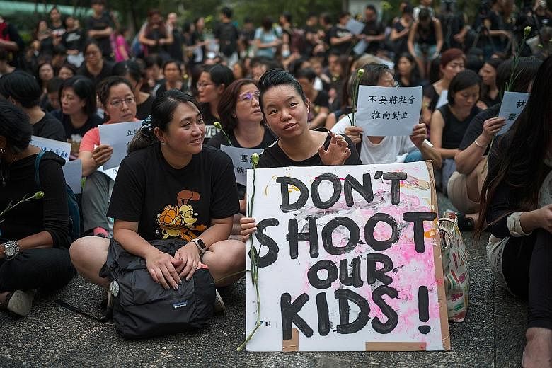 A group of mothers at a rally in Hong Kong yesterday. They started an online petition, signed by tens of thousands, to voice their disagreement with Chief Executive Carrie Lam, who had called the protesters spoilt children. Police standing guard near