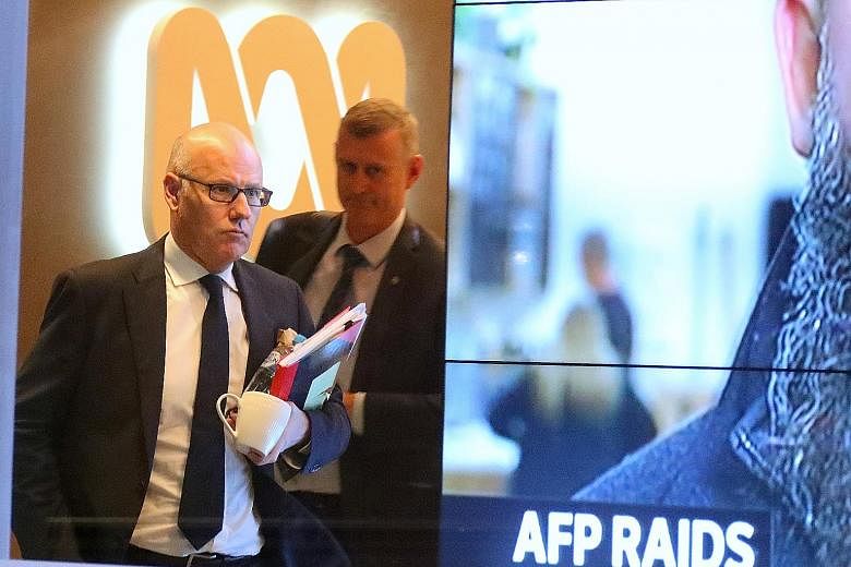 Senior ABC journalist John Lyons (wearing glasses) and an Australian Federal Police officer leaving the national broadcaster's building in Sydney following the June 5 raid. PHOTO: EPA-EFE