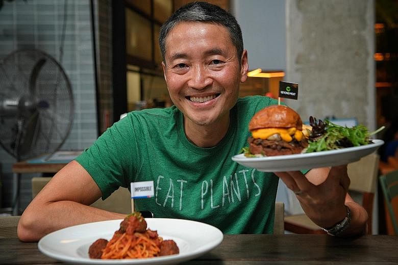 Mr Yuan Oeij, chairman of The Prive Group, with its Impossible Meatball Spaghetti and a burger with a Beyond Meat Patty. Restaurateurs must come up with innovative dishes with the meat alternatives so as to keep patrons interested, he says. 