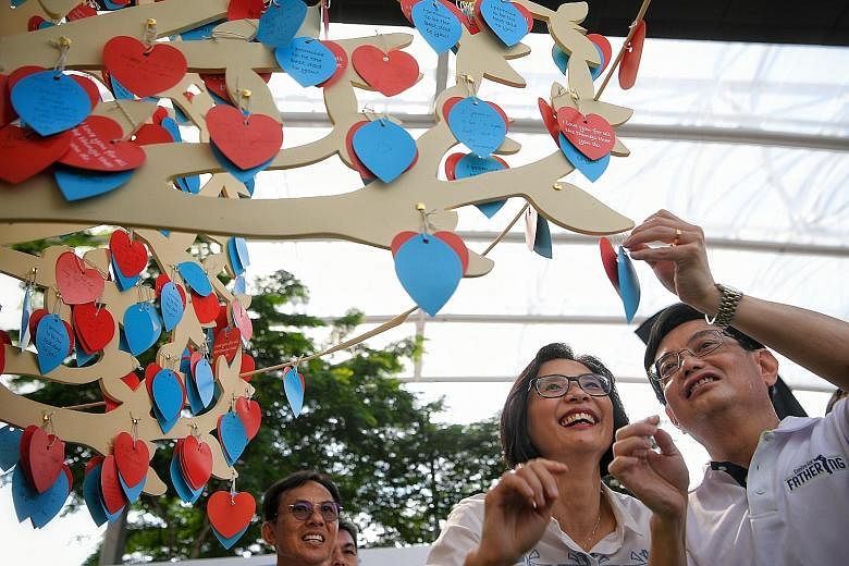 Deputy Prime Minister Heng Swee Keat and Mrs Heng at the "promise tree", where fathers penned their promises to their families while mothers and children wrote notes of appreciation for them, at a Father's Day celebration held at OCBC Square at the S