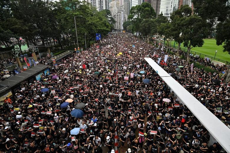 Protesters marching outside Victoria Park in Hong Kong yesterday. Many of those taking part wore black, and the protest continued late into the night, with thousands gathered outside the government complex using their mobile phones as torches.