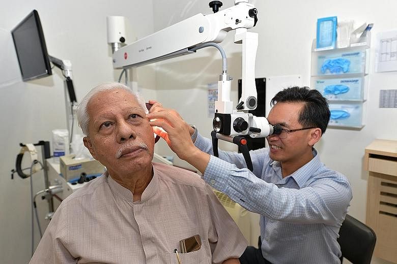 Tan Tock Seng Hospital's senior ear, nose and throat consultant Ho Eu Chin doing an ear check-up on his patient, Mr Doraisamy Pillay.