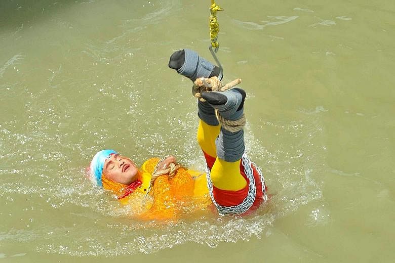 Magician Chanchal Lahiri being lowered into the Hooghly River as he attempted Harry Houdini's famed underwater escape trick in Kolkata on Sunday.