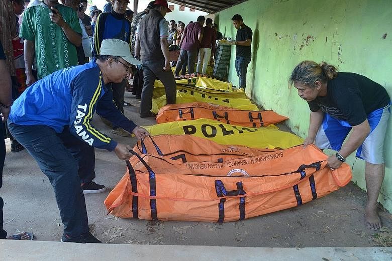 Men arranging body bags containing victims from a boat that sank with 57 people on board, off Sumenep in East Java province on Monday. "The boat was hit by a large wave, overturned and sank," said an East Java police spokesman.