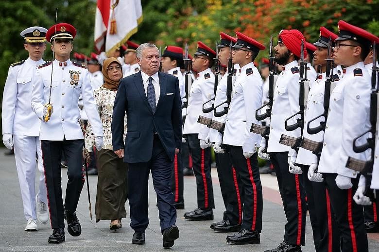 Jordan's King Abdullah II inspecting a guard of honour with President Halimah Yacob at the Istana yesterday. This is the King's third state visit to Singapore.