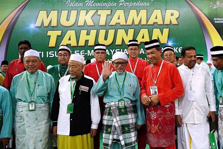 Parti Islam SeMalaysia (PAS) president Hadi Awang waving to delegates, with Umno deputy president Mohamad Hasan (in red) beside him, at the opening of PAS' 65th annual assembly in Kuantan, Pahang, yesterday. Other leaders from the Umno-led Barisan Na