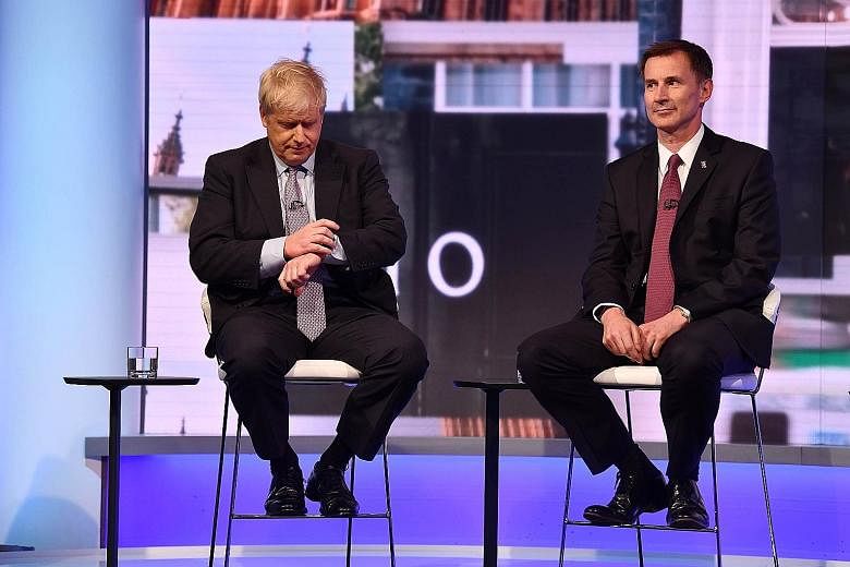Mr Boris Johnson (left) and Mr Jeremy Hunt in a candid moment during a BBC television leadership debate in London on Tuesday. The two angling to be Britain's next leader have vowed to renegotiate the Brexit deal with the EU and get a better one befor