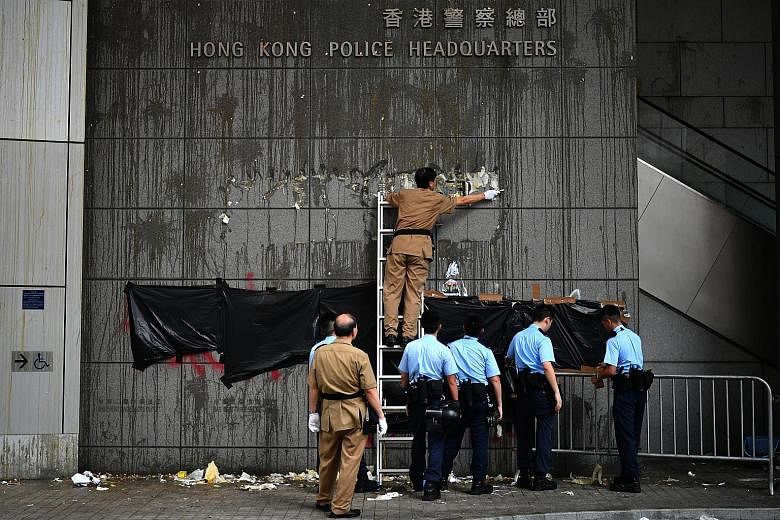 Officers clearing the barricades outside the police headquarters early yesterday morning. The protesters had set up the barricades secured with cable ties to cut off access to the complex. Some security and police personnel cleaning and covering up t