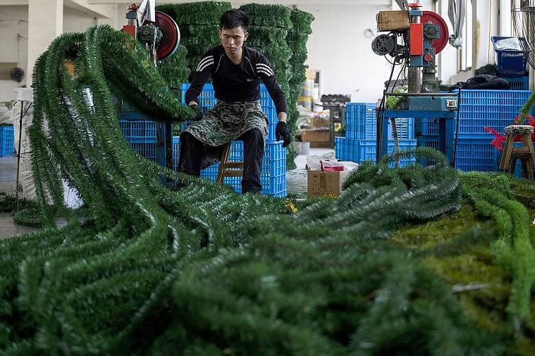 A worker cutting fake Christmas tree branches (left) into pieces in Yiwu, China. Pre-lit artificial Christmas trees (above) sold in the US, all of which are made in China, will be subject to upcoming tariffs together with hundreds of Christmas-time g