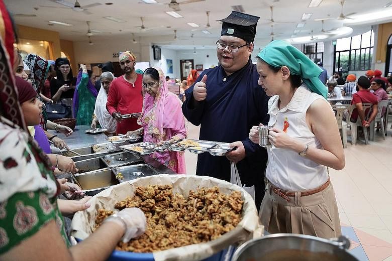 Taoist priest-in-training Kendrick Goh, 23, and fellow learning journey participant Gwee Siew Theng, 49, being served food by volunteers at Silat Road Sikh Temple yesterday. ST PHOTO: KELVIN CHNG