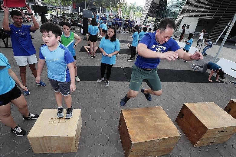 Mr Ng Eng Chuan, a 44-year-old functional fitness coach, and his nine-year-old son Ted doing box jumps at the Singapore Children's Society's annual charity fitness event at Singapore Sports Hub's OCBC Square yesterday. Mettle Challenge, in its third 
