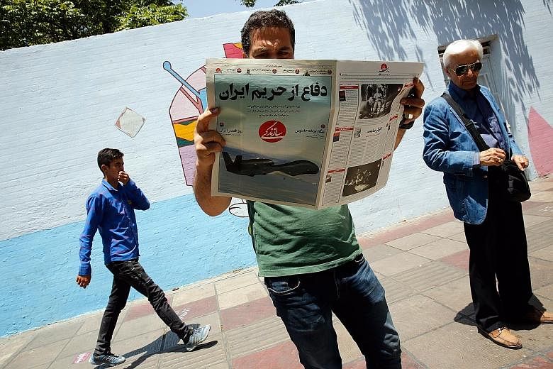 An Iranian reading the Sazandegi newspaper with a picture of a US drone and headline in Persian reading "Defence from Iran border" in Teheran last Saturday. Tensions in the Middle East may play a part in market developments this week. PHOTO: EPA-EFE
