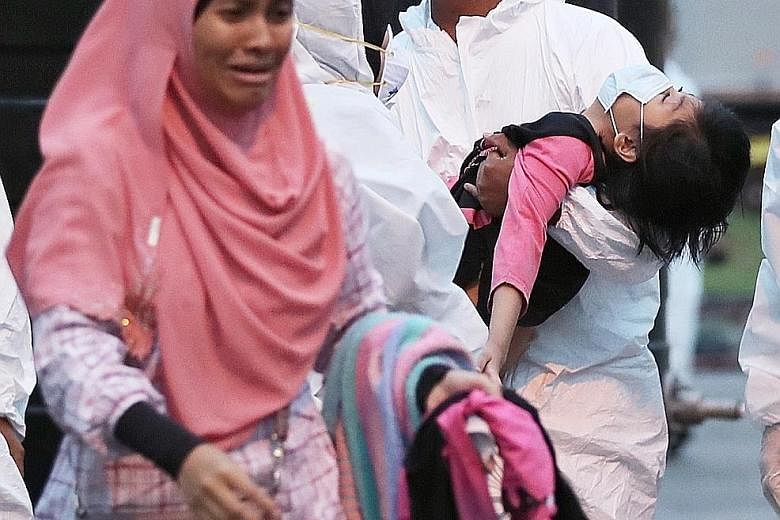 Pupils being decontaminated outside Pasir Gudang Indoor Stadium. Schools in the area have been closed, but officials are no closer to the source of the problem. Medical staff transferring a child from a medical tent to a waiting ambulance at the Pasi