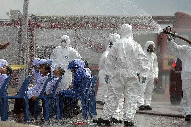 Pupils being decontaminated outside Pasir Gudang Indoor Stadium. Schools in the area have been closed, but officials are no closer to the source of the problem. Medical staff transferring a child from a medical tent to a waiting ambulance at the Pasi