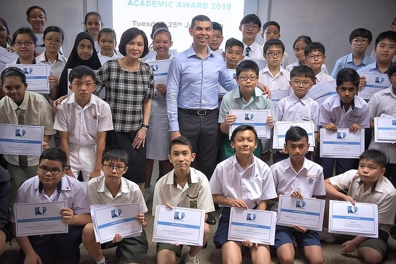 Ms Sarah Chua, vice-president of IT and Mobile, Samsung Electronics Singapore, and Mr Warren Fernandez, chairman of The Straits Times School Pocket Money Fund and editor of The Straits Times, with some of the cash award recipients yesterday. In total