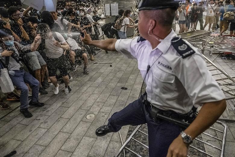 A police officer using pepper spray during clashes with protesters in Hong Kong this month. Britain wants an independent investigation into police violence and will not issue export licences for crowd-control equipment to Hong Kong unless it is satis