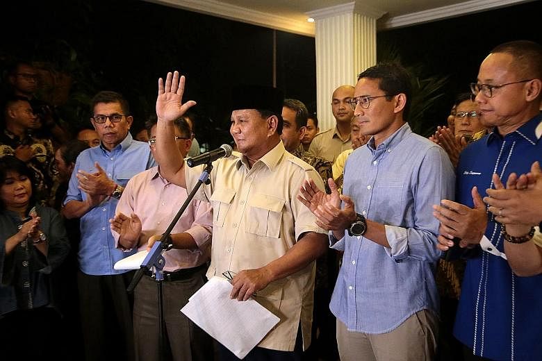 Indonesian presidential candidate Prabowo Subianto (centre) with his running mate Sandiaga Uno (right) at a news conference last night following the Constitutional Court's ruling, which Mr Prabowo said he accepted. Prabowo supporters shouting slogans