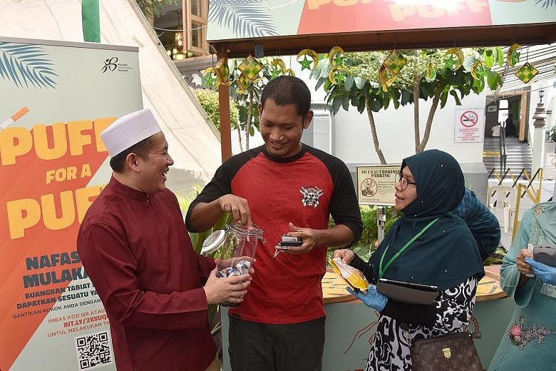 Senior Parliamentary Secretary for Health Amrin Amin collecting cigarettes at the Puff For A Puff booth in Sultan Mosque yesterday.