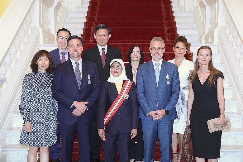 President Halimah Yacob at the investiture of The Public Service Medal last Thursday, flanked by (front row, second from left) Mr Wayne Russell Allan, ASML executive vice-president and Mr Oliver Tonby, senior partner and Asia chairman of McKinsey and