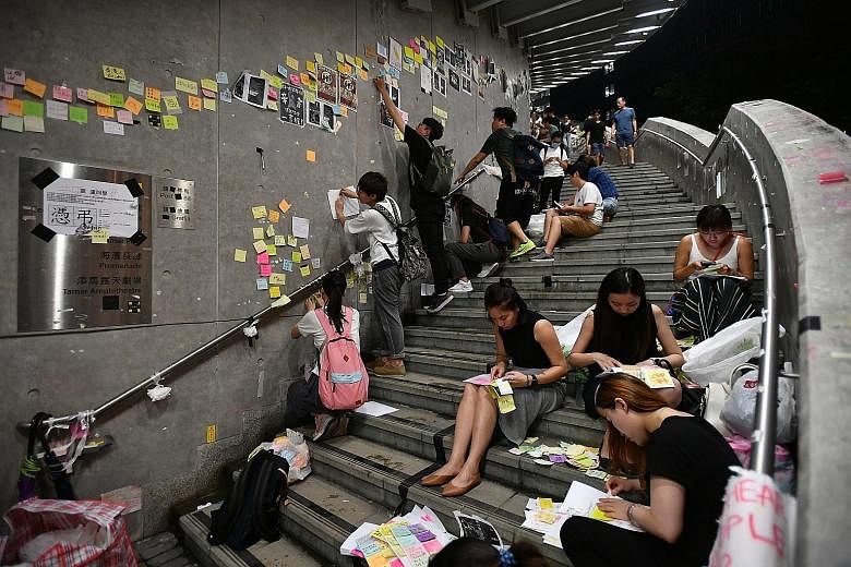 People removing Post-it notes with messages about democracy and universal suffrage from the "Lennon Wall" at the Central Government Complex in Hong Kong yesterday. ST PHOTO: LIM YAOHUI