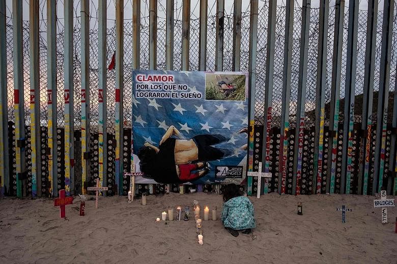 A girl lighting candles in front of a poster of Mr Oscar Alberto Martinez Ramirez and his daughter, Valeria, who both drowned.
