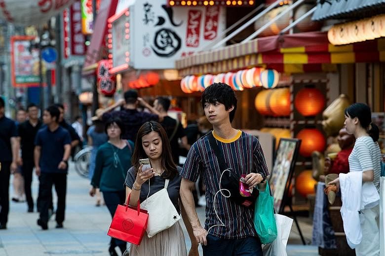 Pedestrians on a shopping street in Osaka. The Japanese government has scheduled an increase in the sales tax to 10 per cent from 8 per cent in October. Aware that the hike could hurt spending, Tokyo is pinning its hopes on mobile payments, an indust