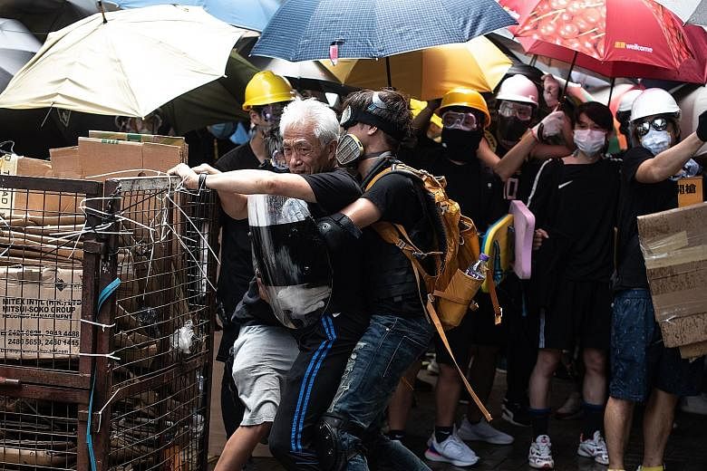 Hong Kong pro-democracy lawmaker Leung Yiu-chung (left) being held back by protesters as he tries to stop them from trying to break a window at the government headquarters on Monday, the 22nd anniversary of the city's handover from Britain to China. 
