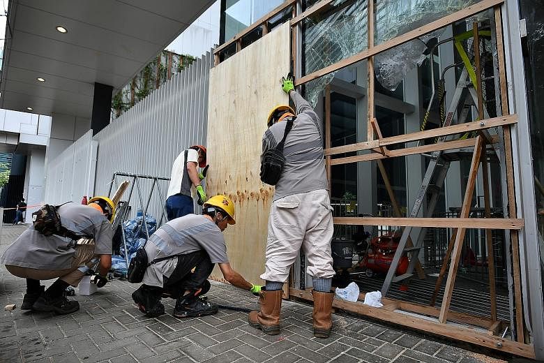 Police at the Legislative Council Complex yesterday. China has increasingly been critical of what it calls Western instigation to stir trouble. ST PHOTO: LIM YAOHUI Workers putting up a wooden hoarding yesterday to cover shattered glass panels at the